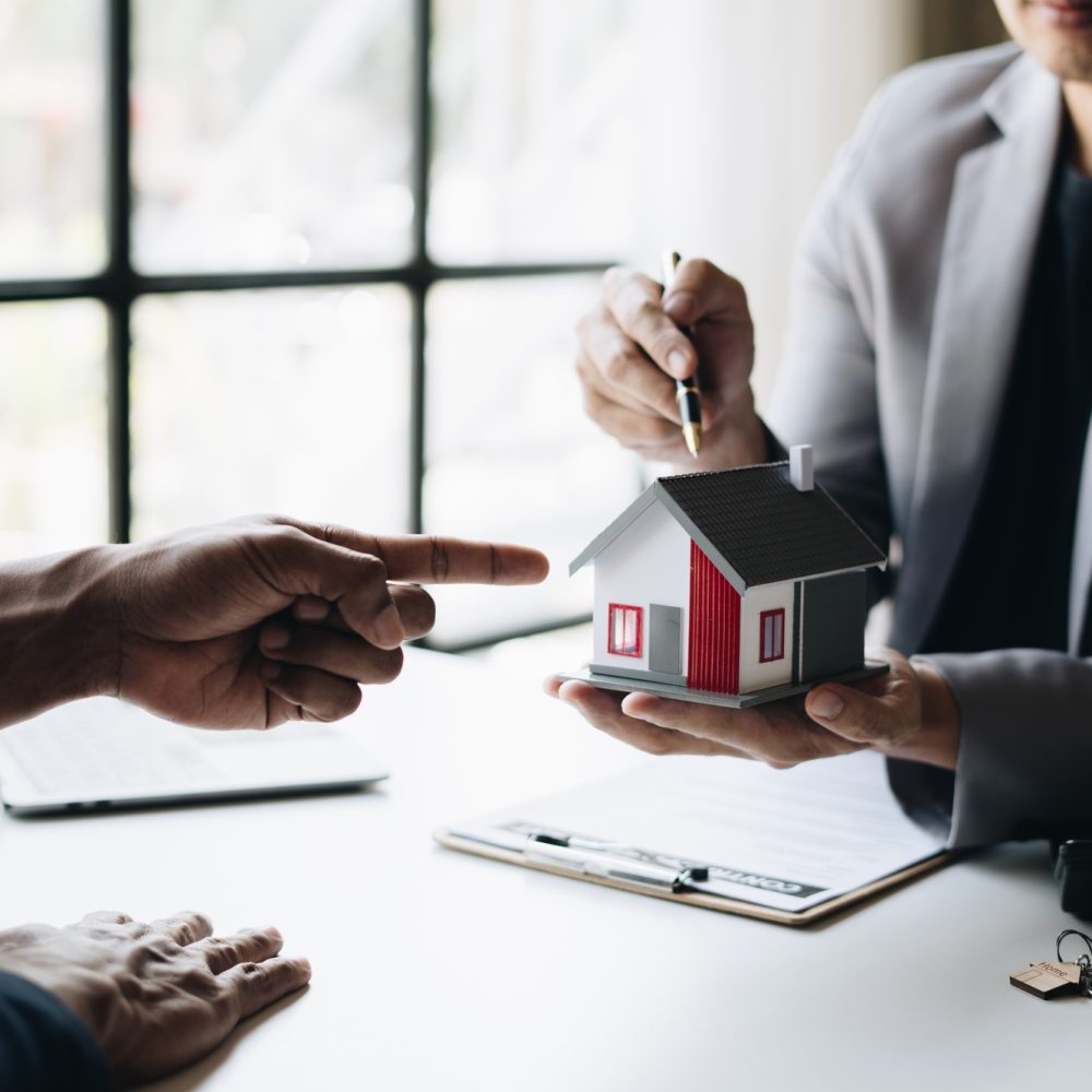 Real estate agent holding house key to his client after signing contract,concept for real estate.